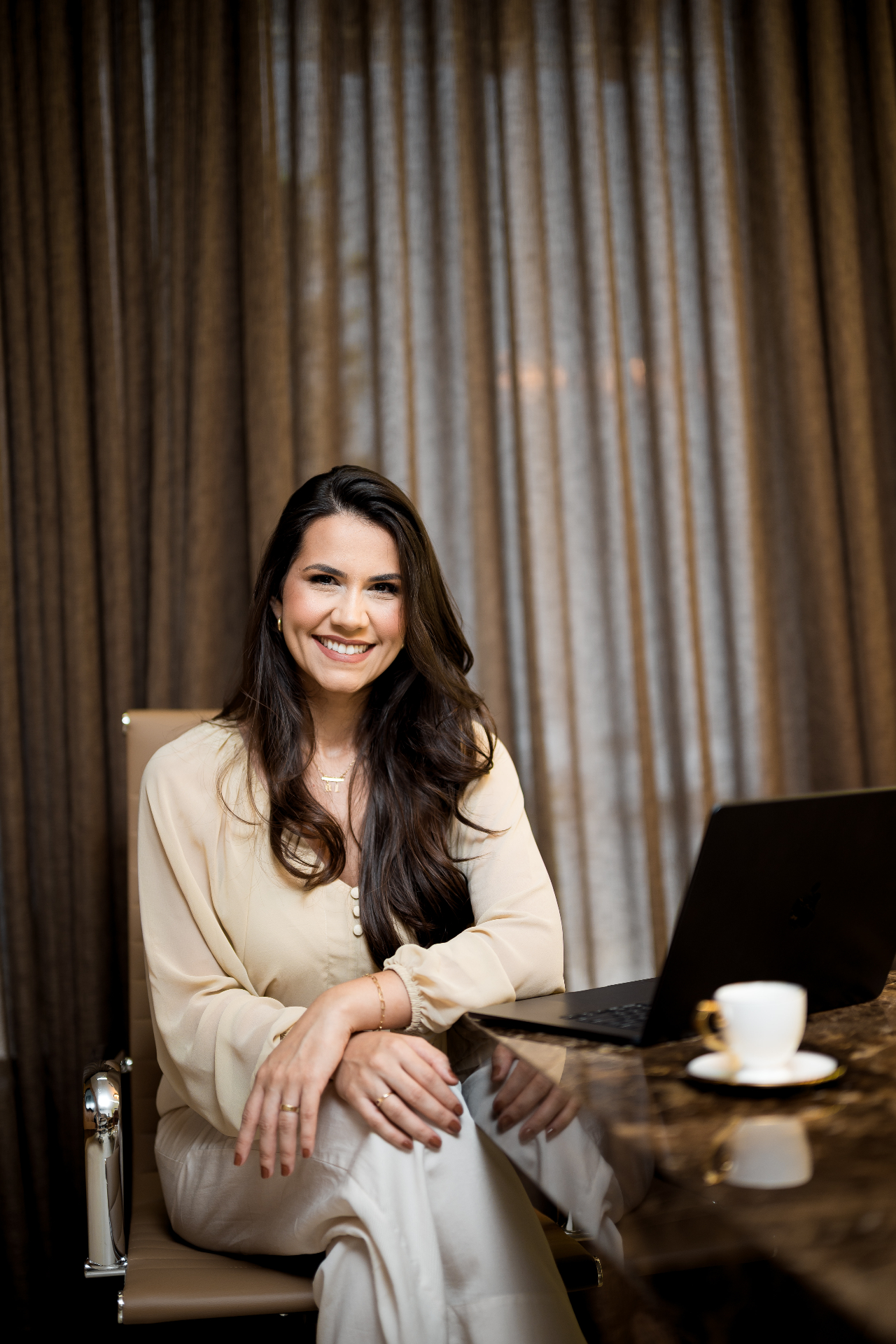 Carolina Diamantino sorrindo à mesa de reunião com notebook